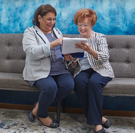 Dental team member sitting on couch looking at paperwork with dental patient