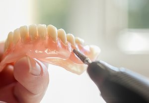 Lab technician altering a full denture in the lab