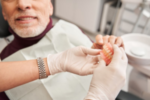 Dentist examining patient’s broken dentures